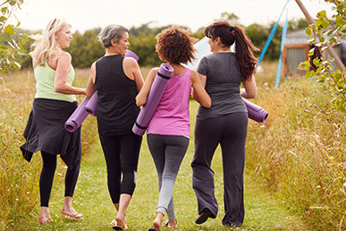 Image from behind of women walking with yoga mats